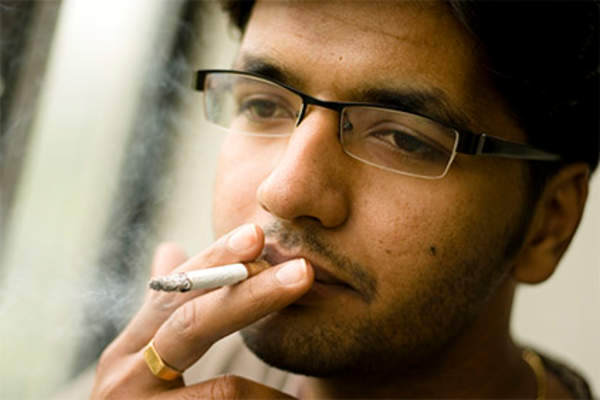 Young man with glasses smoking.