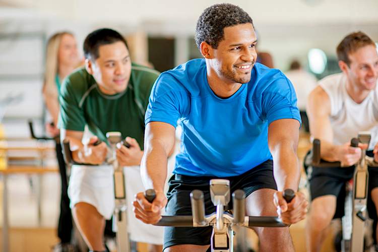 Men on exercise bikes in a gym.