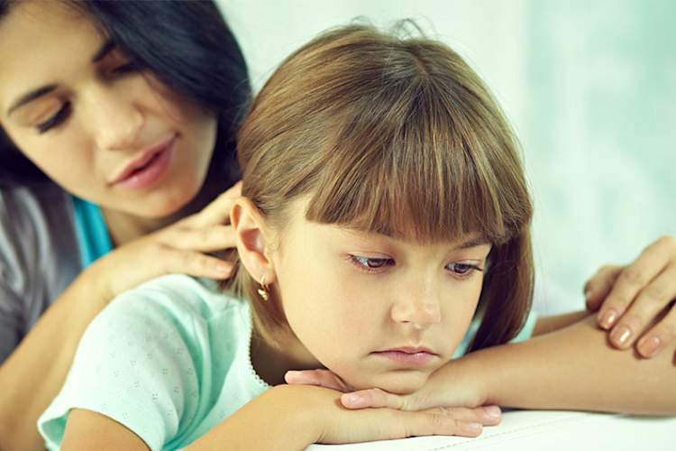 Mother comforting her young daughter who has a headache.