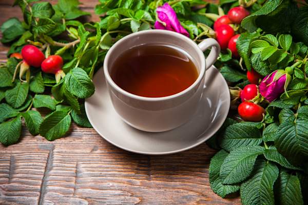 Healthy tea with a dogrose on wooden table