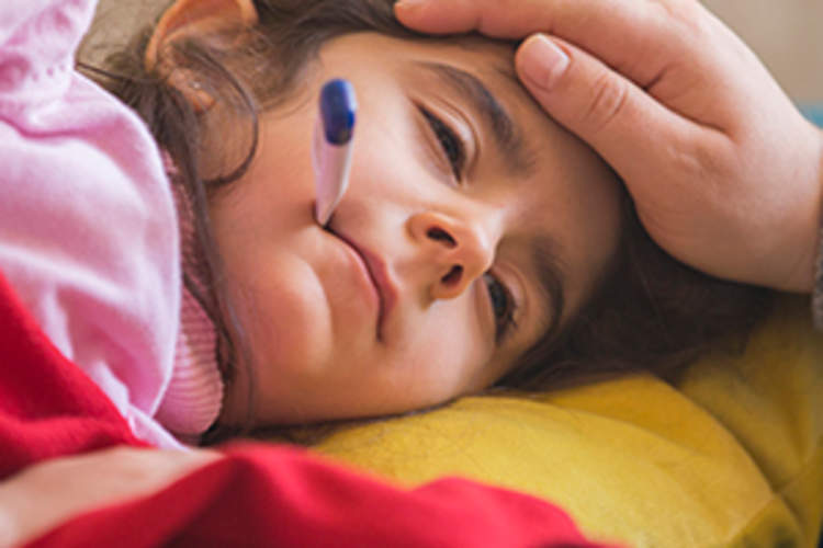 Mother checking on sick daughter laying in bed