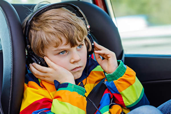 Young boy wearing headphones in the car.