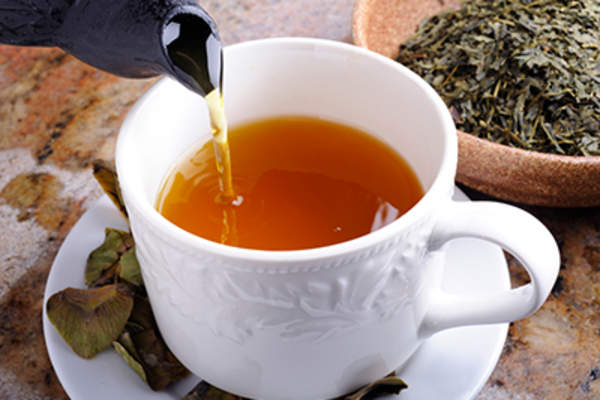 Pouring green tea into a cup.