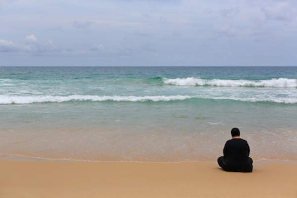 Lonely person sitting on beach.