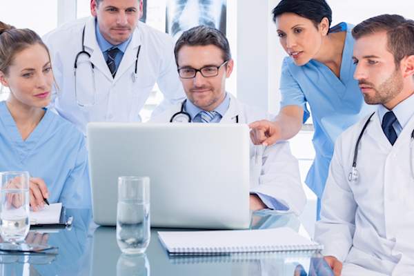 Doctors huddled around a laptop.