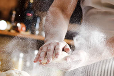 Close up of male baker hands kneading dough
