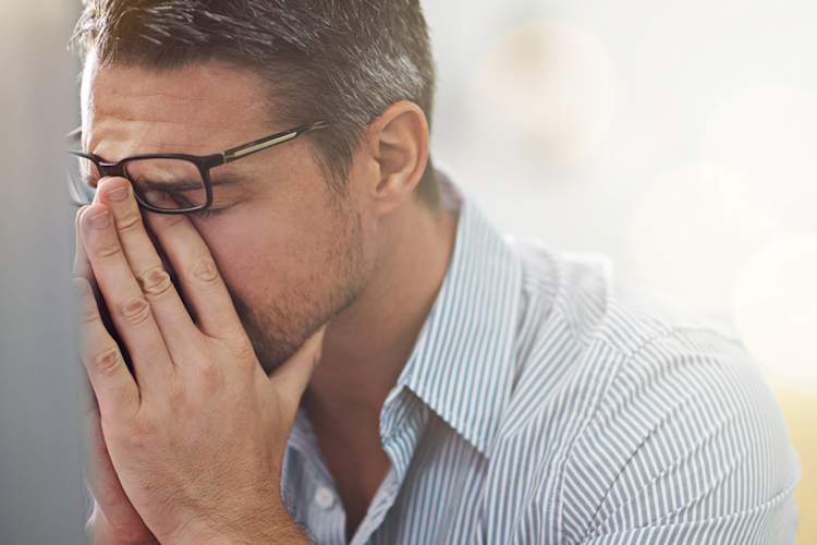 Man looks distressed at a a computer screen.