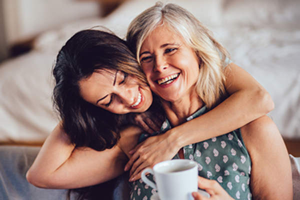 Mother and daughter hugging and laughing.