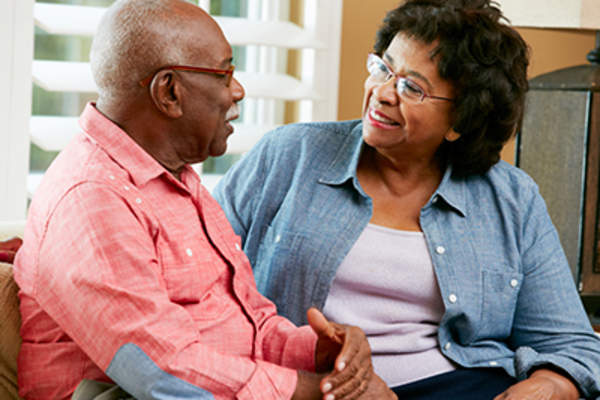 Senior couple smiling and talking at home.