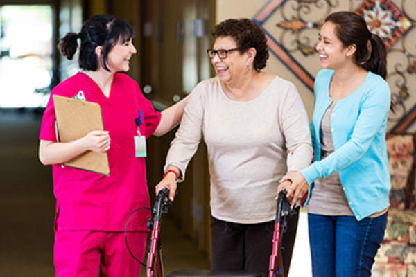 Nurse walks with senior woman in nursing home.