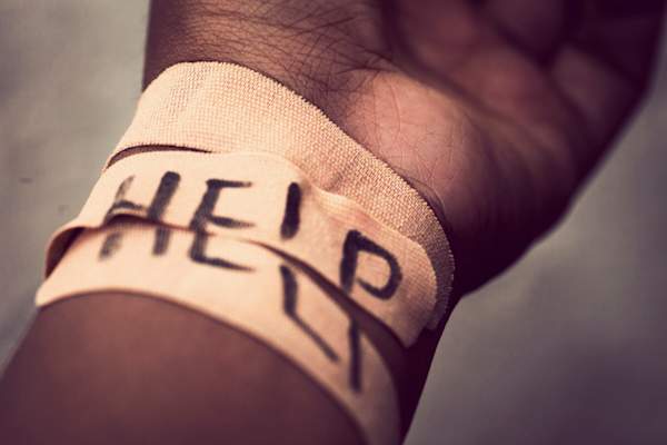Self-harm wrist covered with bandage, with "HELP" written across bandage.