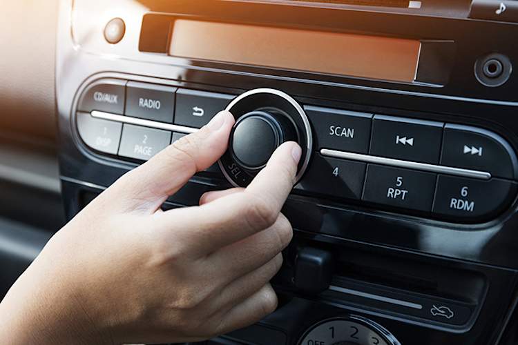 Woman turning down the volume of music in a car.