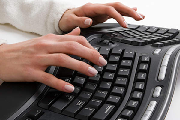 Woman typing on an ergonomic keyboard.