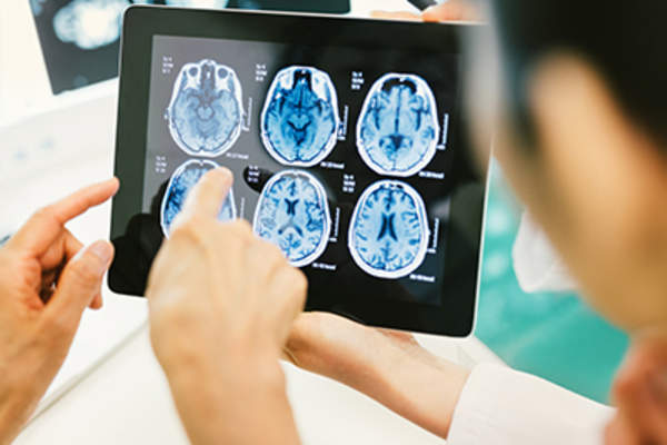Doctor and patient using digital tablet to look at brain scans.