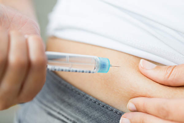 Close up of hands making injection by insulin pen.