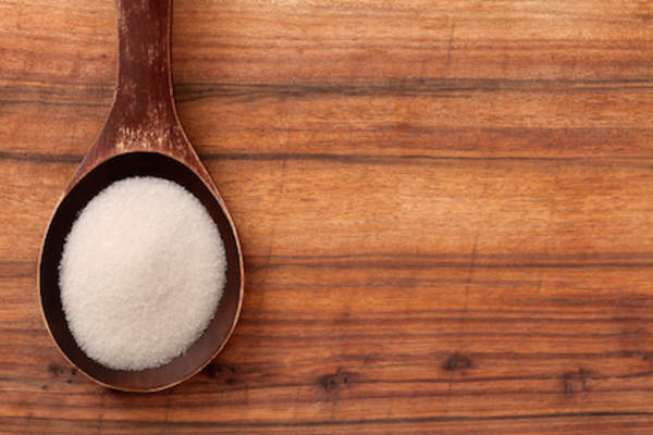 Refined sugar on wooden spoon.