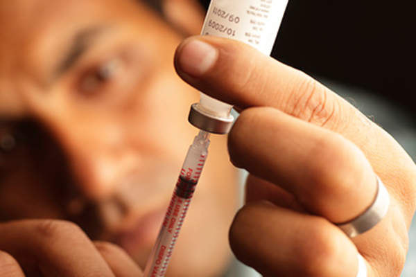 Man withdrawing bone agent from a vial to treat prostate cancer.