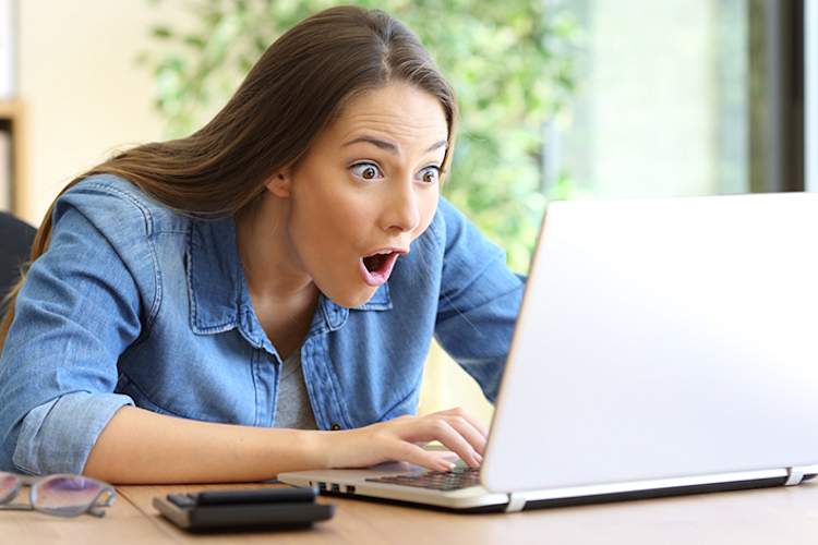 Young woman surprised by something on her laptop.