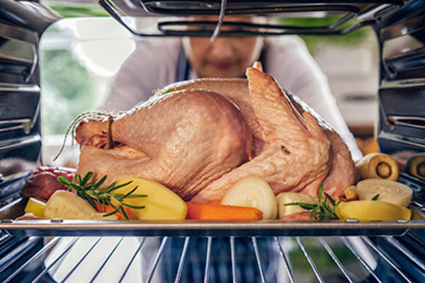 Woman putting a turkey into the oven.