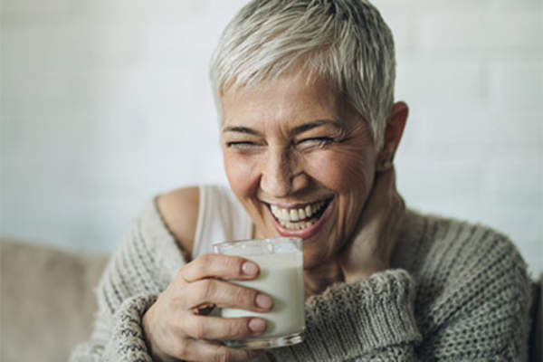 Smiling mature woman drinking milk.