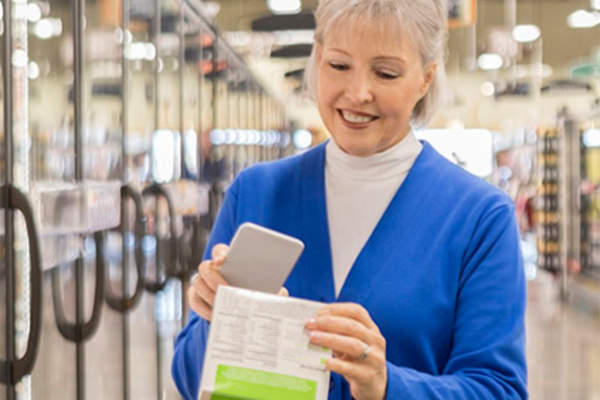 Woman using smartphone at grocery store.