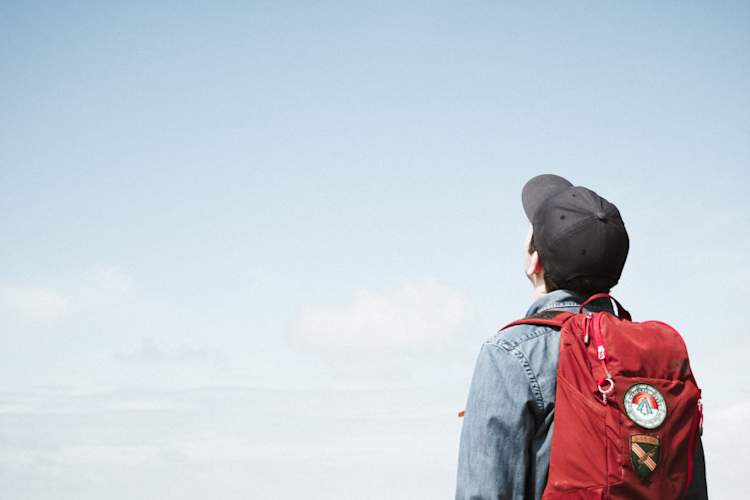 young man in backpack looking at sky