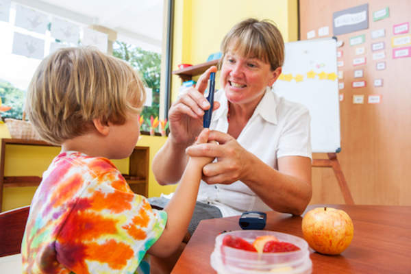 School nurse helping child test blood sugar.
