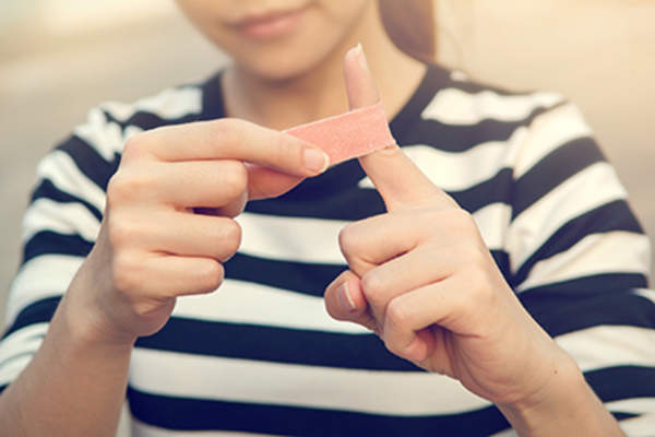 Wrapping a cut with a bandaid.