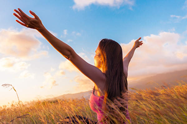 Woman feeling happy, arms raised outside.