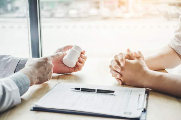 doctor pointing to pill bottle with patient