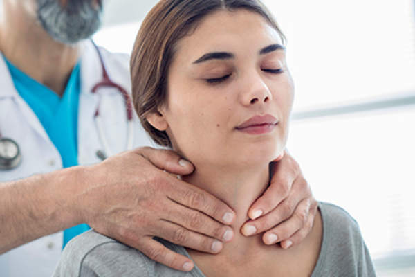 Doctor examining female patient's neck.