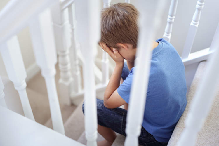 Young boy, upset, sitting on stairs.