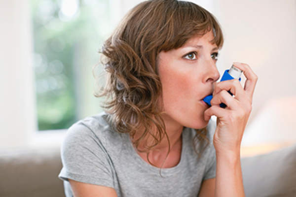 Mid adult woman using asthma inhaler