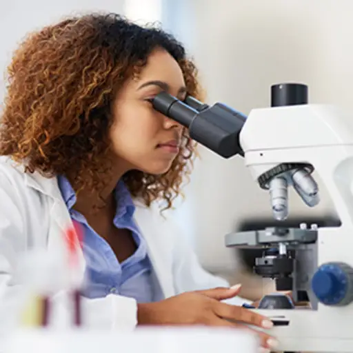 Scientist peering through microscope.
