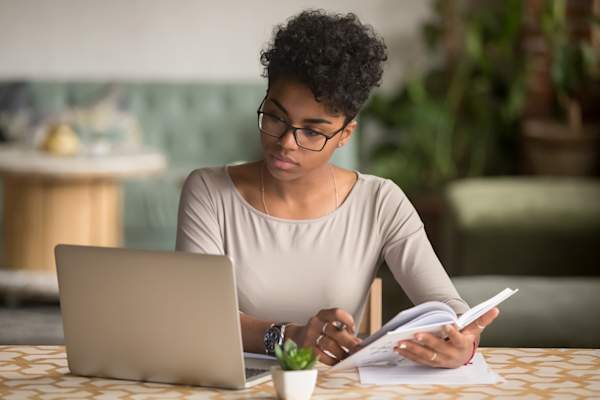 young woman looking at computer taking notes