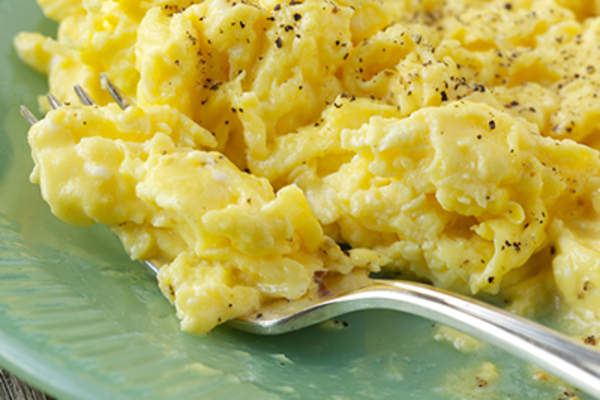 Fresh scrambled eggs on a green plate.