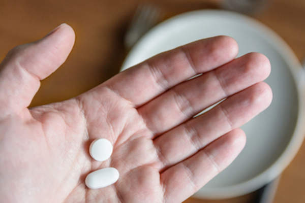 White pills in hand.