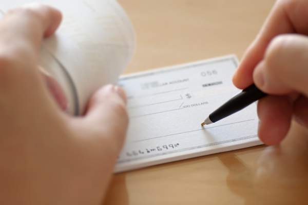 Person writes a check for donation.