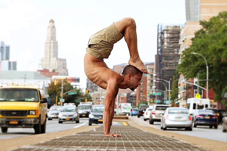 A man does yoga on a busy city street.