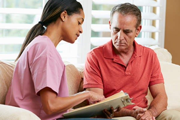 A nurse going through details during a visit with concerned man.