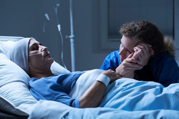 one sister sitting next to other sister's hospital bed
