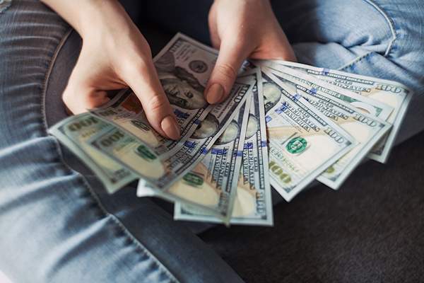 Woman's hand holding hundred dollar bills