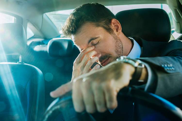 Man drowsy driving rubbing eyes.