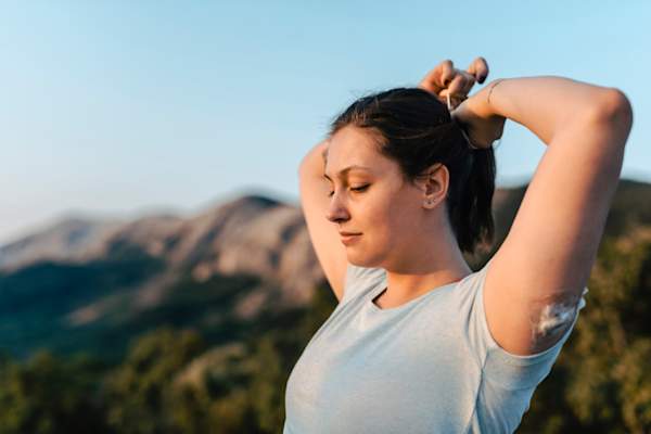 Woman with diabetes wearing a CGM and making a ponytail