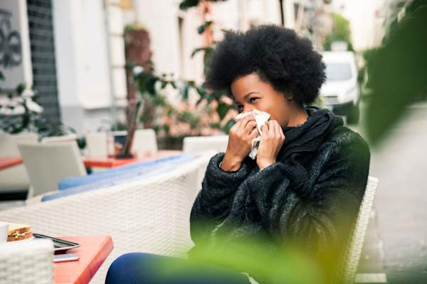 Woman blowing nose outside of cafe