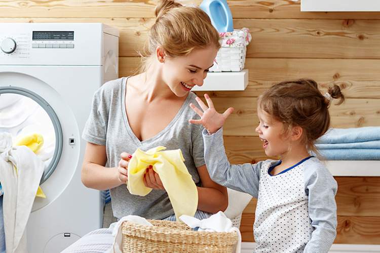 Mother and young daughter folding laundry.