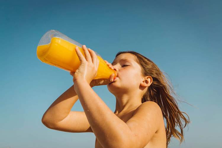 child on the beach drinking juice