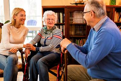 Adult daughter spending time with senior parents at home.
