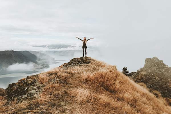 woman standing on cliff arms outstretched