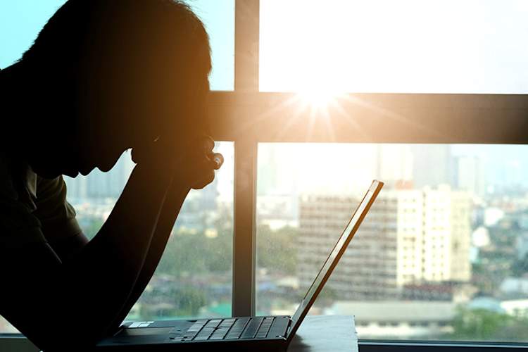 Woman at desk in city office with migraine headache.